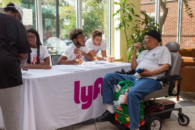 A resident from Philadelphia Housing Authority's Nellie Reynolds Gardens development speaks with staffers from Lyft at the Grocery Access Program kickoff.